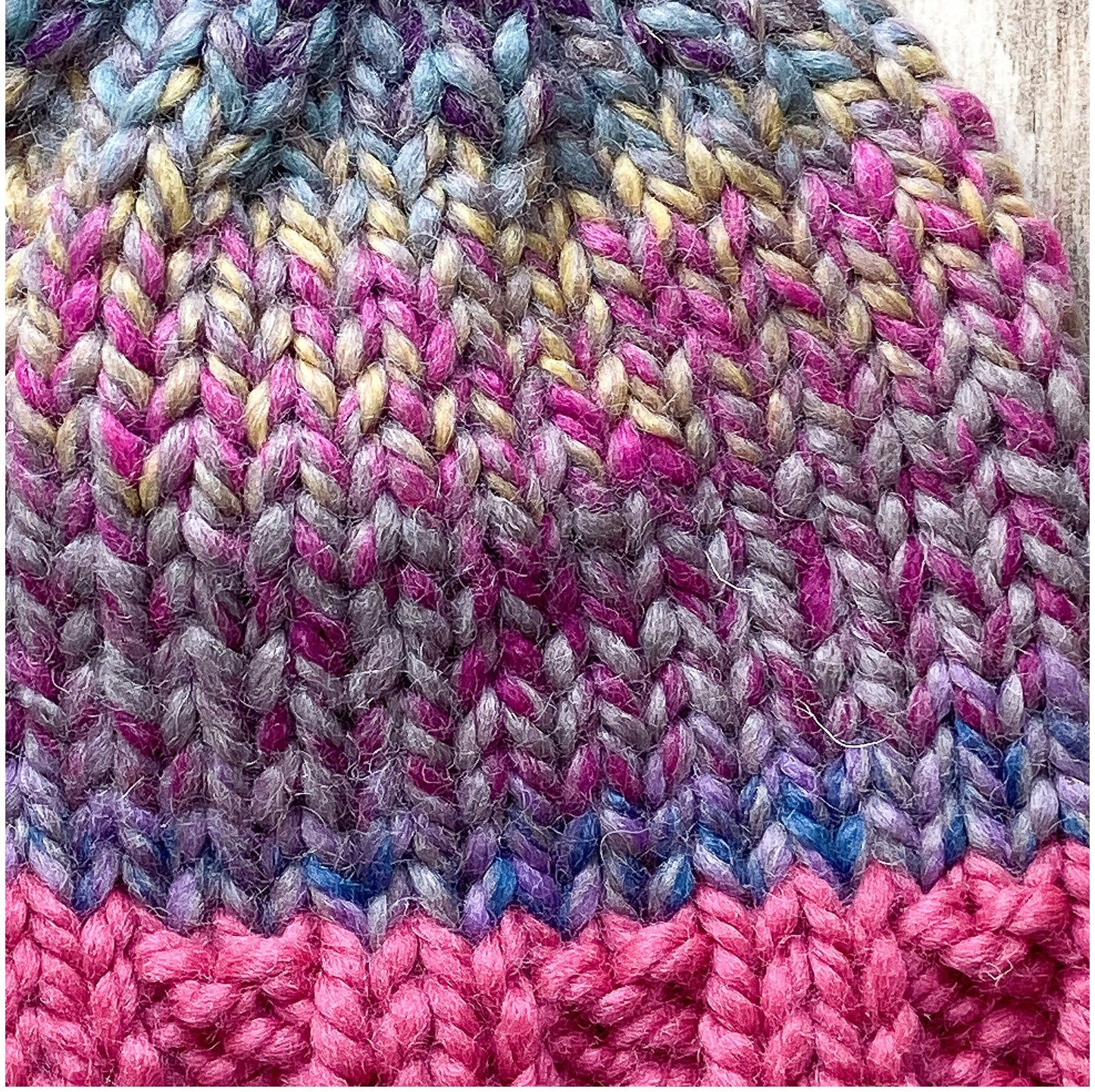 Child's wool beanie hand-knit in a multi-colored yarn with raspberry brim